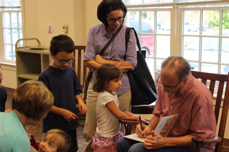 Daniel Wallace signing his children's book The Cat's Pajamas for a family of young readers at the library.