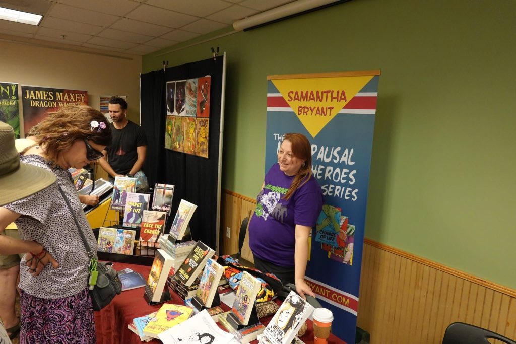 Samantha Bryant at her Menopausal Superheroes table at the library comics fair.