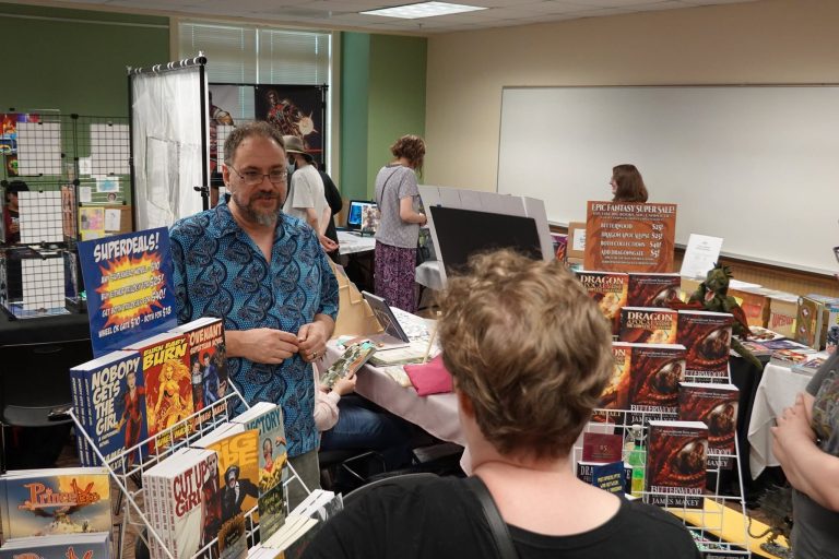 Visitors browsing creator tables at the library comics fair.
