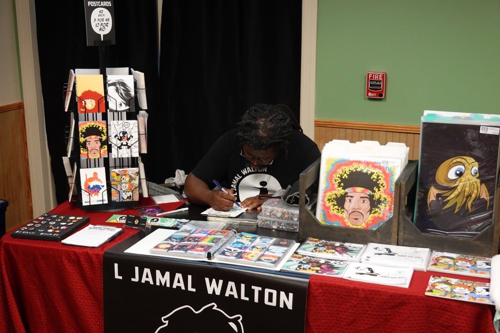 Comic creator L Jamal Walton signing at his table at the library comics fair.