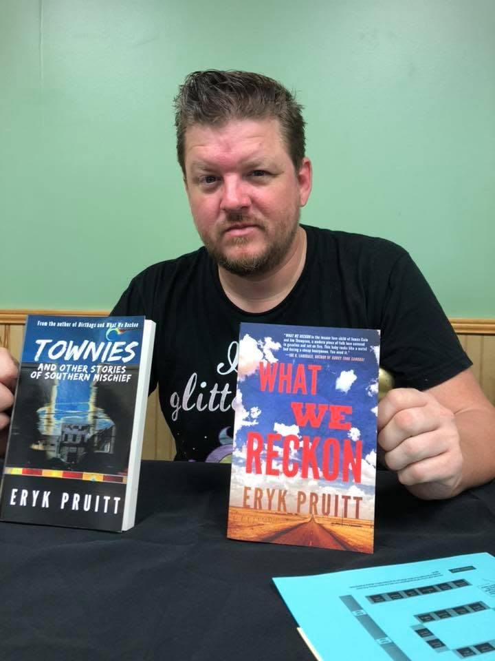 Eryk Pruitt holding Townies and What We Reckon at the Local Author Book Fair.