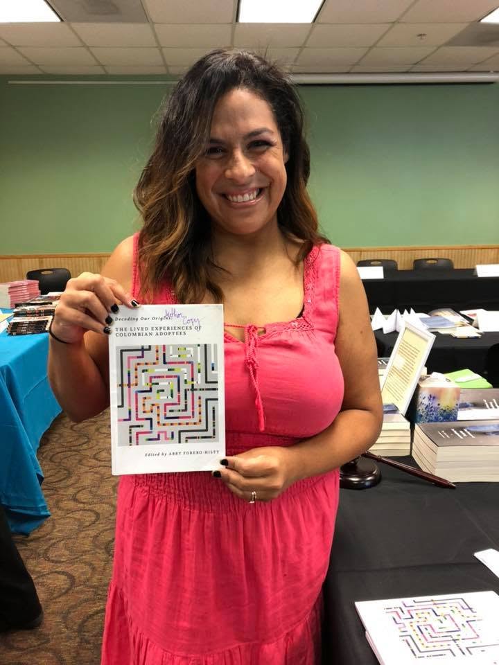 Alexis Thomas holding her book at the Local Author Book Fair.