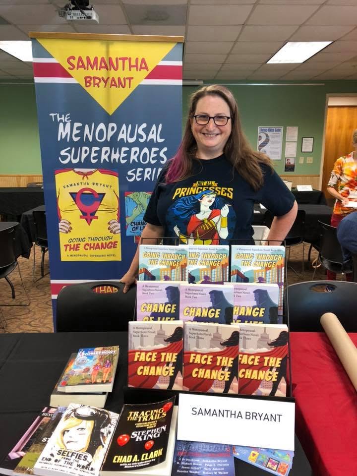 Samantha Bryant under her Menopausal Superheroes banner at the Local Author Book Fair.