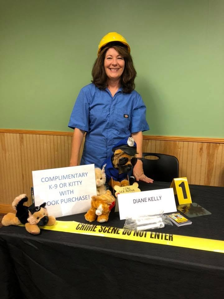 Diane Kelly in costume with crime scene tape at her mystery table at the Local Author Book Fair.