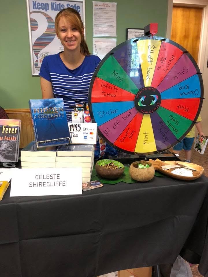 Celeste Shirecliffe with a prize wheel at the Local Author Book Fair.